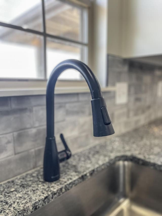 interior details featuring a sink and dark stone countertops