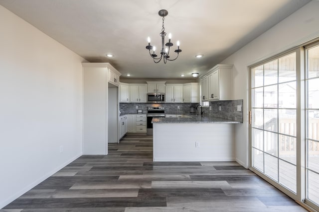 kitchen with a peninsula, appliances with stainless steel finishes, backsplash, and a sink