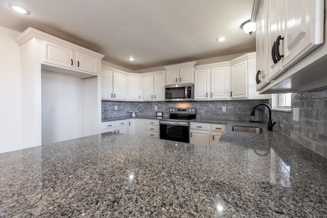 kitchen with backsplash, dark stone counters, stainless steel appliances, and a sink