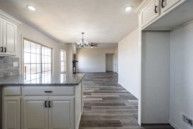 kitchen featuring a notable chandelier, a peninsula, dark wood-type flooring, white cabinetry, and backsplash