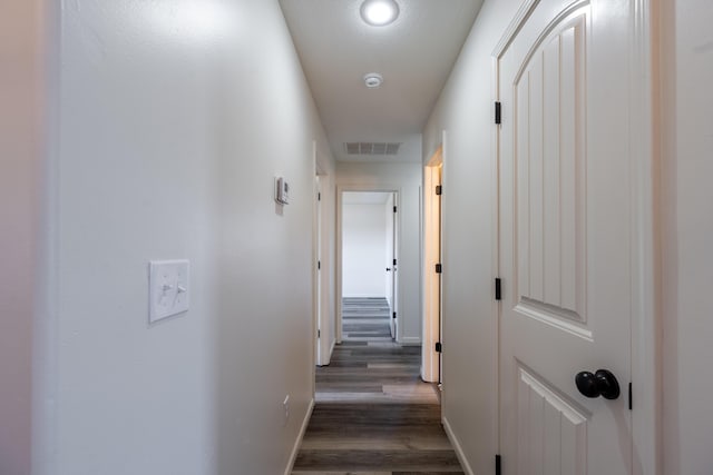 corridor with wood finished floors, visible vents, and baseboards