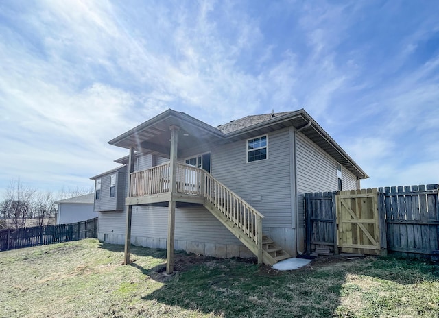 back of property with a gate, fence, stairway, and a lawn