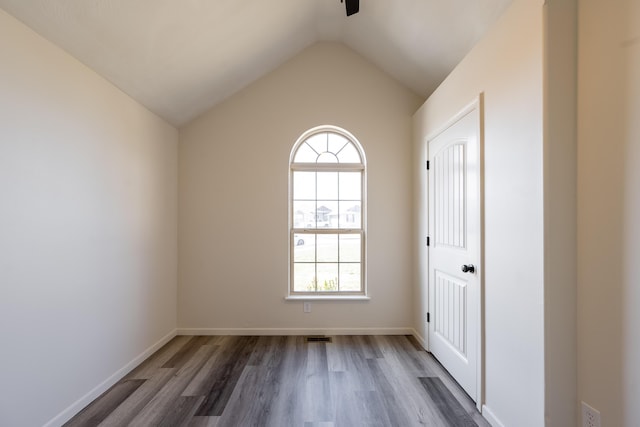 unfurnished room featuring baseboards, vaulted ceiling, and wood finished floors