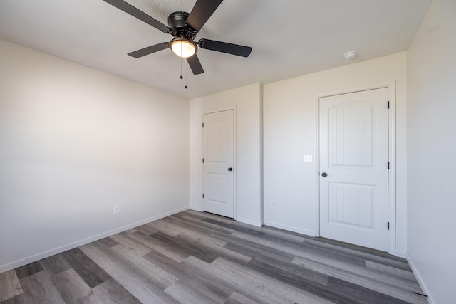 unfurnished bedroom featuring wood finished floors, a ceiling fan, and baseboards