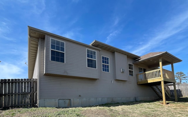 rear view of house featuring fence, a wooden deck, and stairs