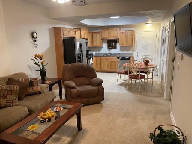 living room featuring baseboards, a tray ceiling, and light colored carpet