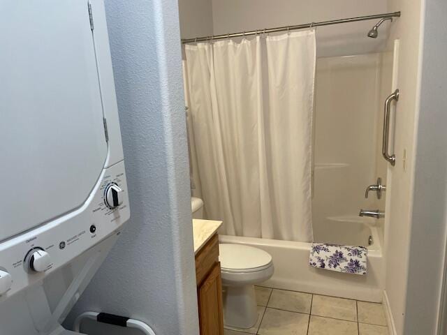 bathroom featuring tile patterned flooring, toilet, stacked washer / dryer, vanity, and shower / bath combo