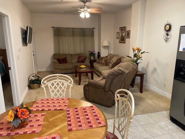 living room featuring light tile patterned flooring, ceiling fan, and baseboards