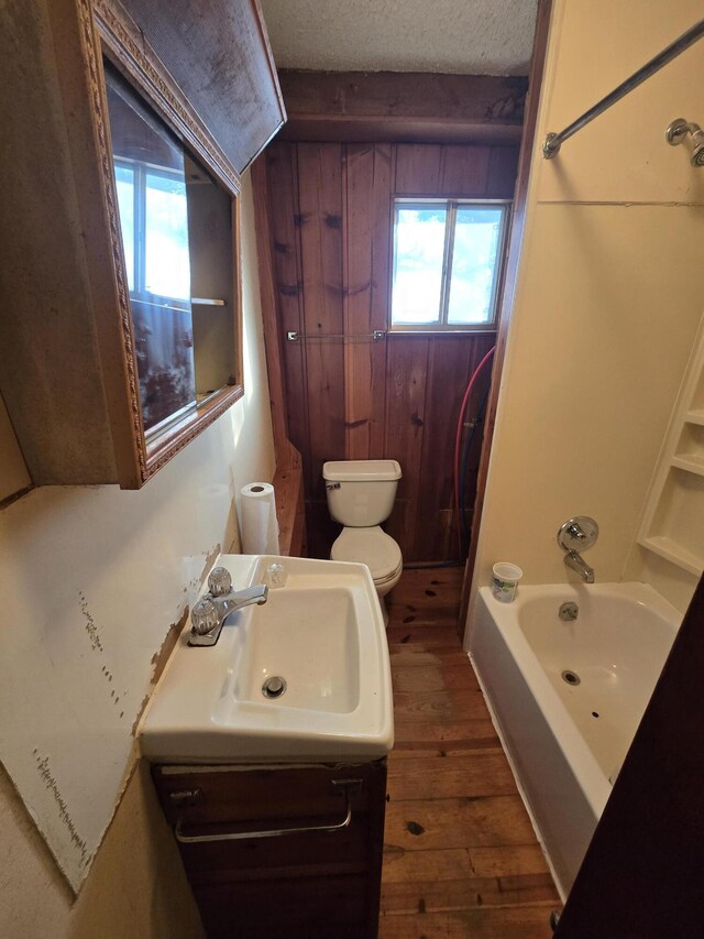 full bathroom featuring a textured ceiling, toilet, wood finished floors, vanity, and shower / bathing tub combination