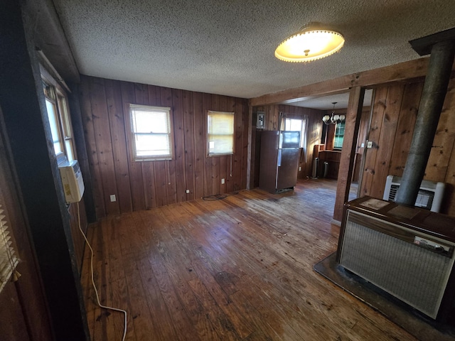 entryway with a textured ceiling, a notable chandelier, heating unit, hardwood / wood-style floors, and a wood stove