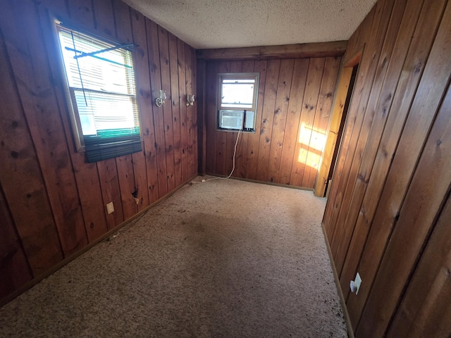 unfurnished room featuring carpet floors, wooden walls, and a textured ceiling