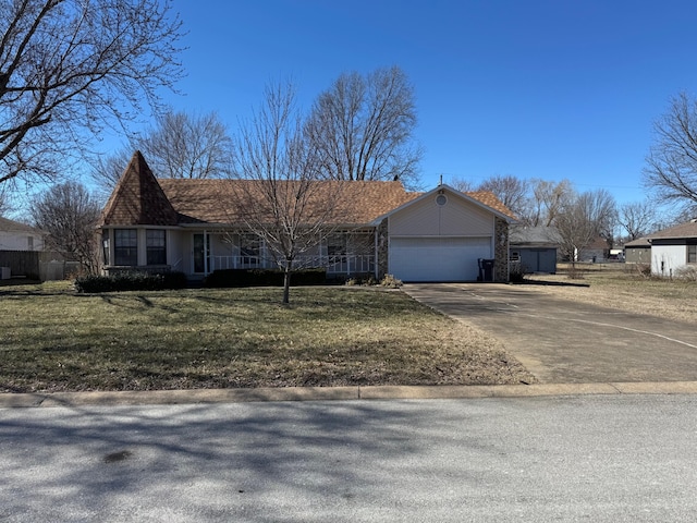 single story home featuring a front yard, concrete driveway, covered porch, and an attached garage