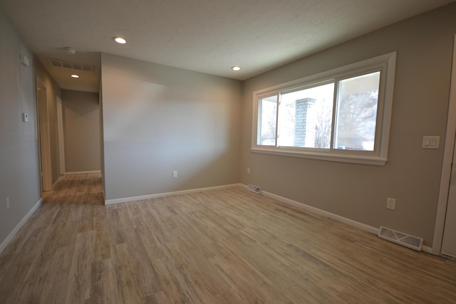 unfurnished room with visible vents, baseboards, and wood finished floors