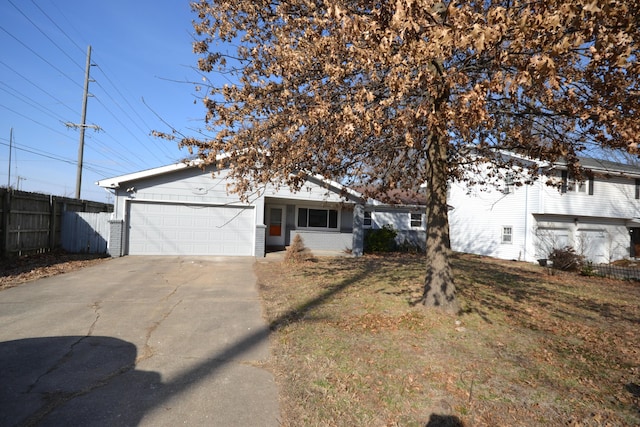 view of front of house with an attached garage, fence, concrete driveway, and brick siding