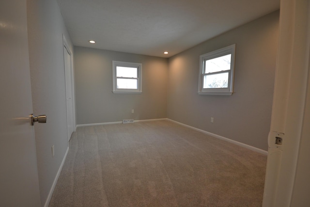 spare room featuring light carpet, baseboards, visible vents, and recessed lighting