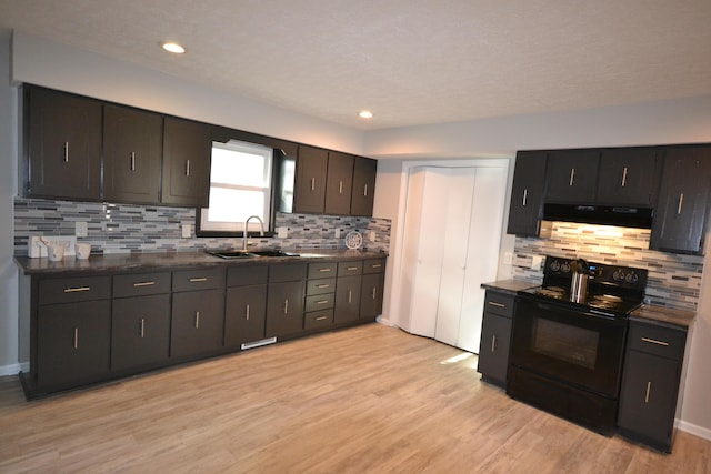 kitchen featuring exhaust hood, a sink, light wood-style floors, black electric range oven, and dark countertops