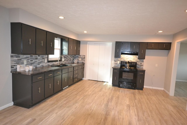 kitchen featuring a sink, dark countertops, light wood-style flooring, and black electric range oven