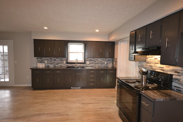 kitchen with black electric range, under cabinet range hood, and dark countertops