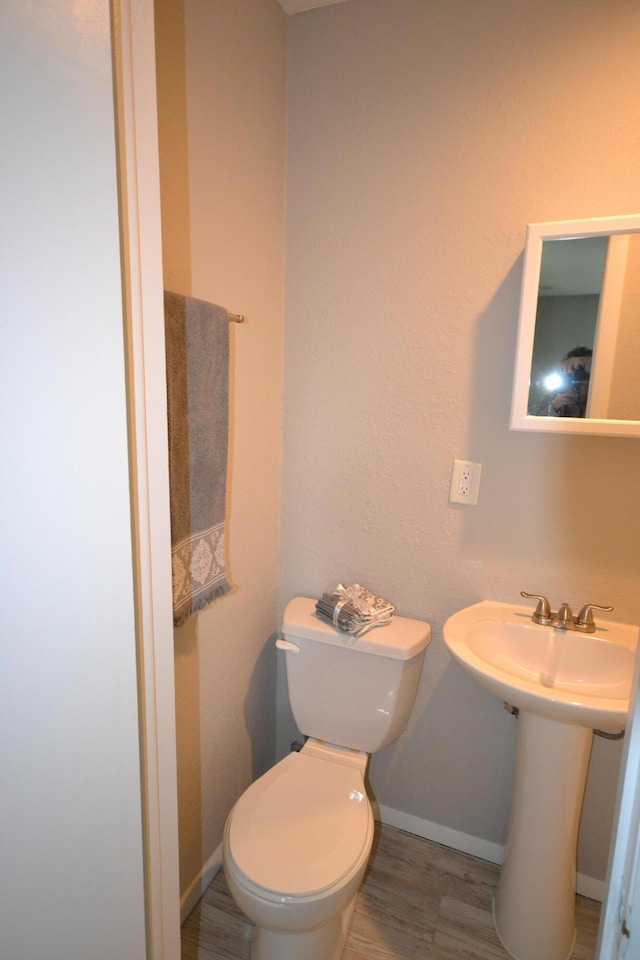 bathroom featuring baseboards, toilet, and wood finished floors