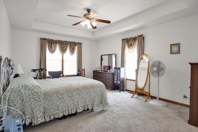 bedroom with carpet, a raised ceiling, ceiling fan, and baseboards