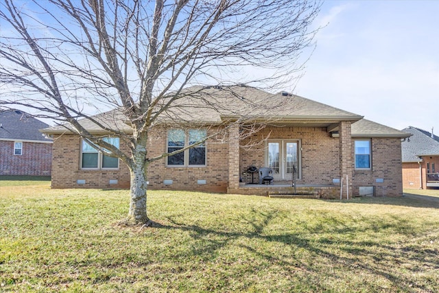 back of property with french doors, brick siding, a yard, a shingled roof, and crawl space