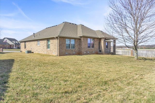 back of property with a yard, brick siding, crawl space, and fence