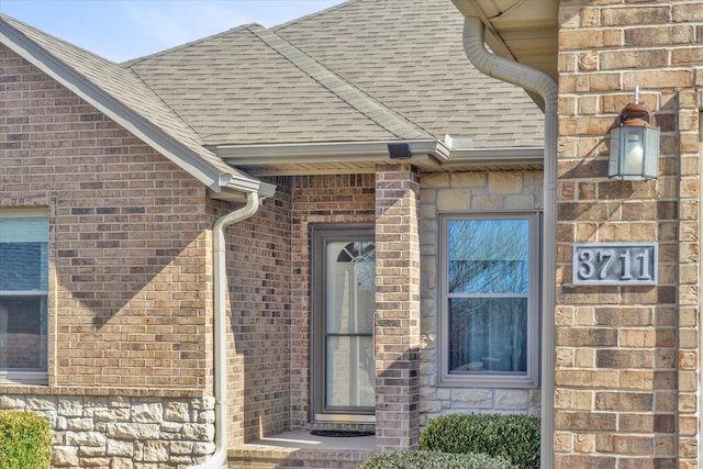 property entrance with brick siding and a shingled roof