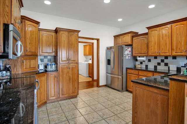 kitchen with stainless steel appliances, independent washer and dryer, decorative backsplash, and brown cabinets