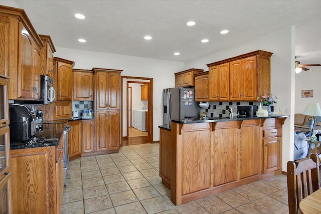 kitchen featuring appliances with stainless steel finishes, backsplash, brown cabinets, and a peninsula