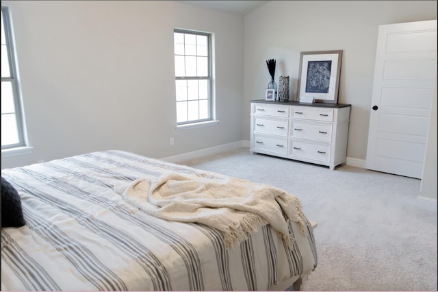 bedroom with baseboards and light colored carpet