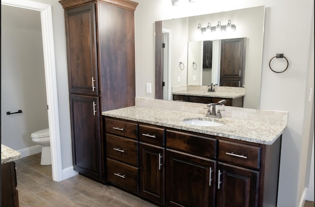 full bathroom with baseboards, vanity, toilet, and wood finished floors