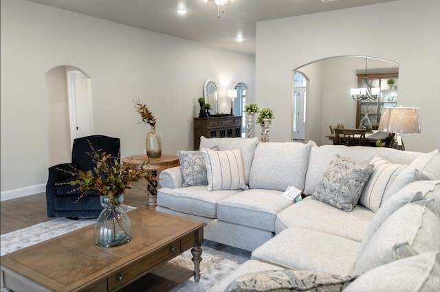 living area with baseboards, arched walkways, a chandelier, and wood finished floors