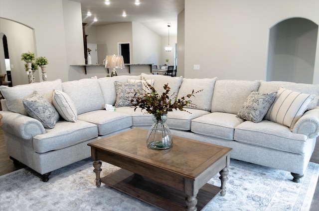 living area featuring arched walkways, vaulted ceiling, and recessed lighting