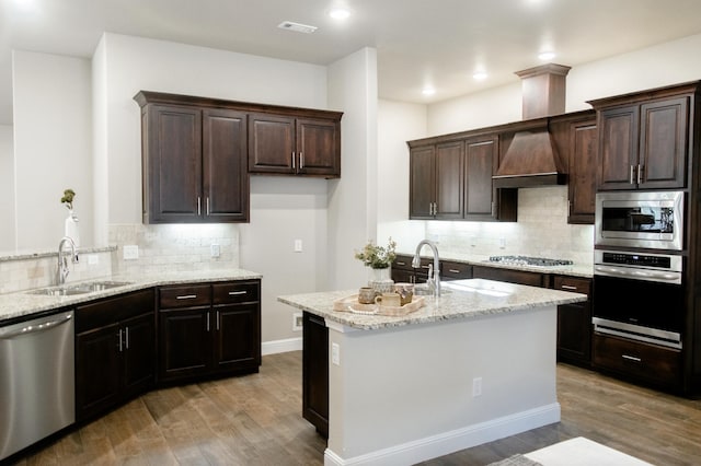 kitchen with light wood finished floors, visible vents, light stone counters, stainless steel appliances, and a sink