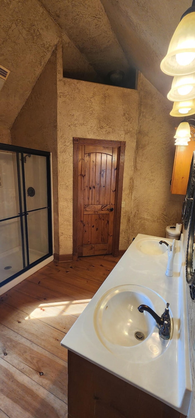 full bathroom featuring lofted ceiling, hardwood / wood-style floors, double vanity, and a sink