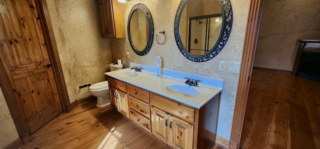 bathroom with toilet, wood-type flooring, double vanity, and a sink
