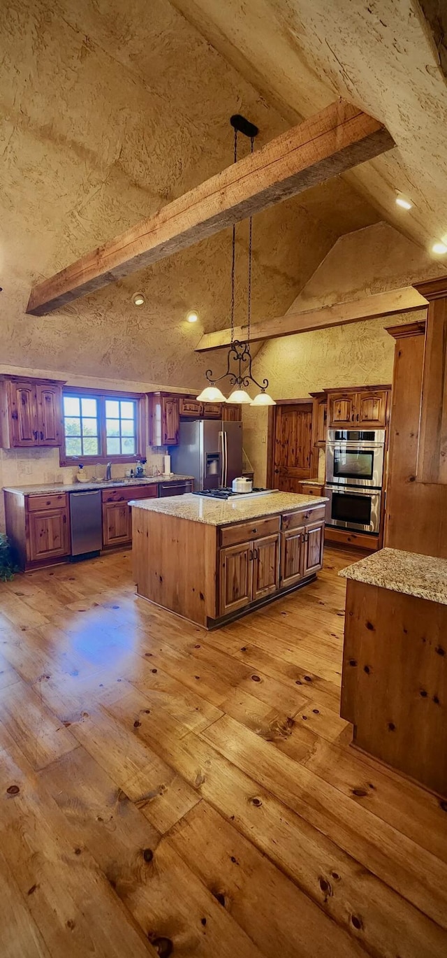 kitchen with light wood finished floors, appliances with stainless steel finishes, beamed ceiling, and a center island
