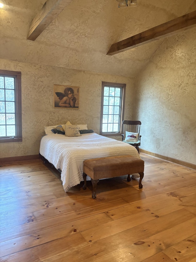 bedroom featuring lofted ceiling with beams, baseboards, and hardwood / wood-style floors