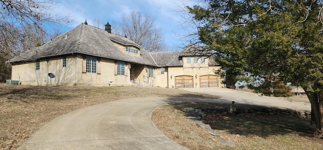 view of front of property featuring concrete driveway, a chimney, and cooling unit