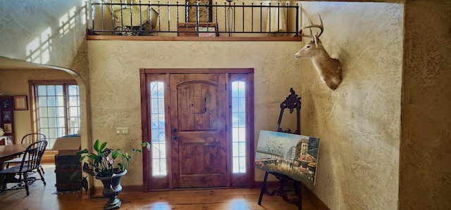 entryway featuring hardwood / wood-style flooring, baseboards, arched walkways, and a textured wall