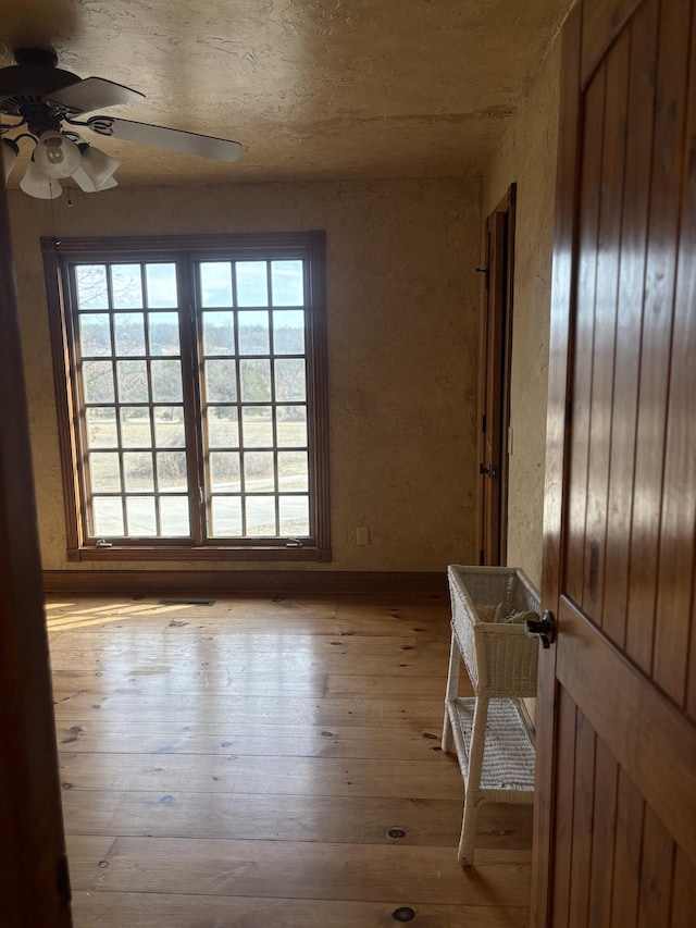 unfurnished room with ceiling fan, plenty of natural light, and wood-type flooring