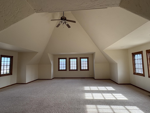 additional living space featuring baseboards, high vaulted ceiling, and light colored carpet