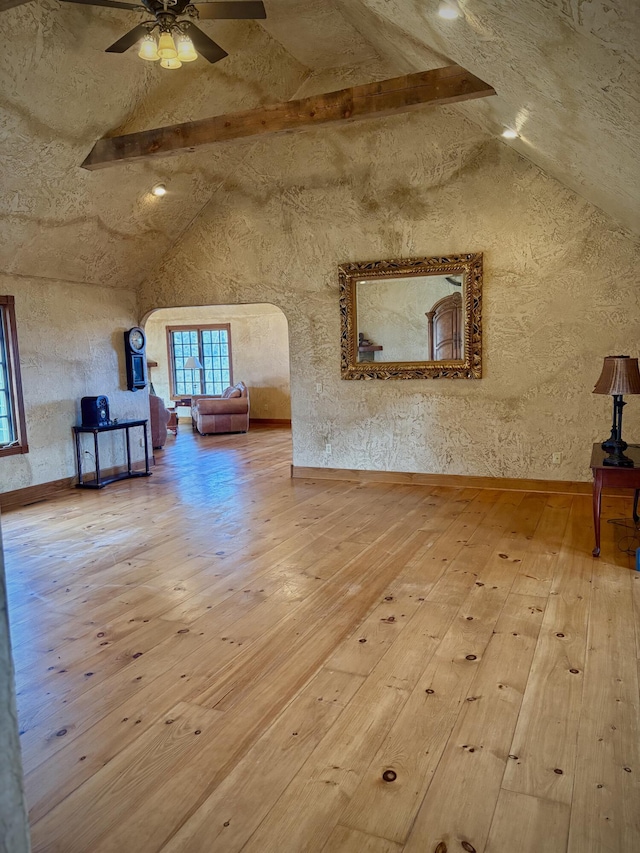 additional living space featuring arched walkways, high vaulted ceiling, hardwood / wood-style flooring, a ceiling fan, and beam ceiling