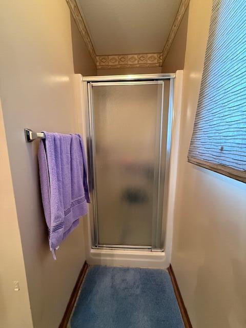 full bathroom with a shower stall and baseboards