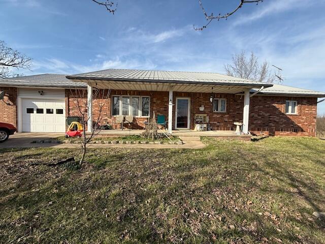 view of front of property with a garage, covered porch, driveway, and brick siding