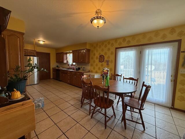 dining space with light tile patterned flooring and wallpapered walls