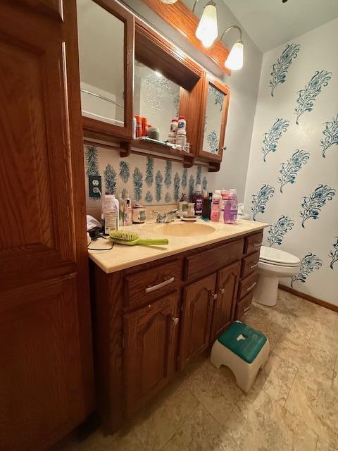 bathroom with baseboards, vanity, and toilet