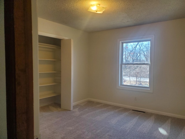 unfurnished bedroom with a closet, visible vents, carpet flooring, a textured ceiling, and baseboards