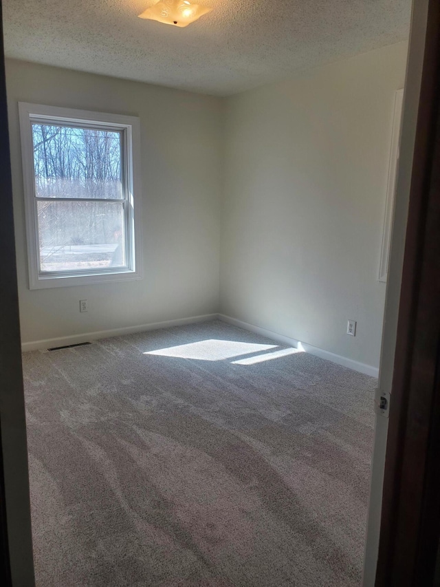 carpeted spare room featuring baseboards and a textured ceiling