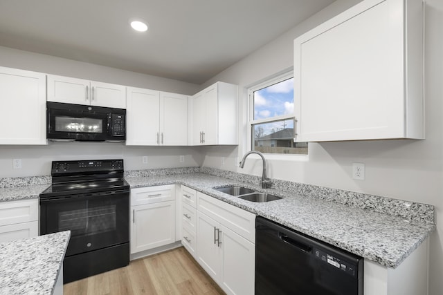 kitchen featuring white cabinetry, black appliances, and a sink